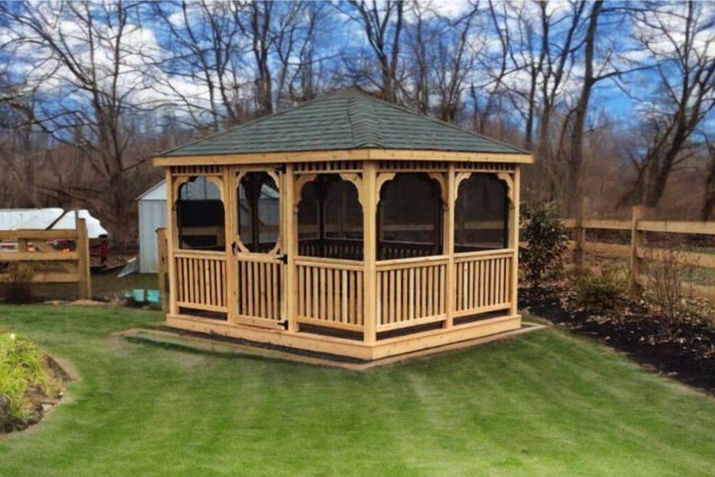 wooden screened gazebo in front of trees
