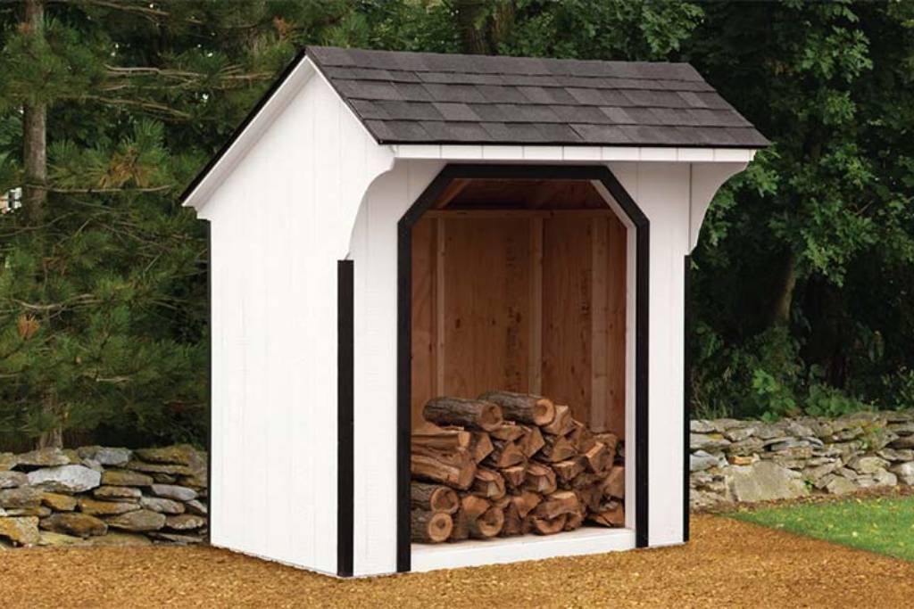 rustic storage shed for wood with white siding and black trim